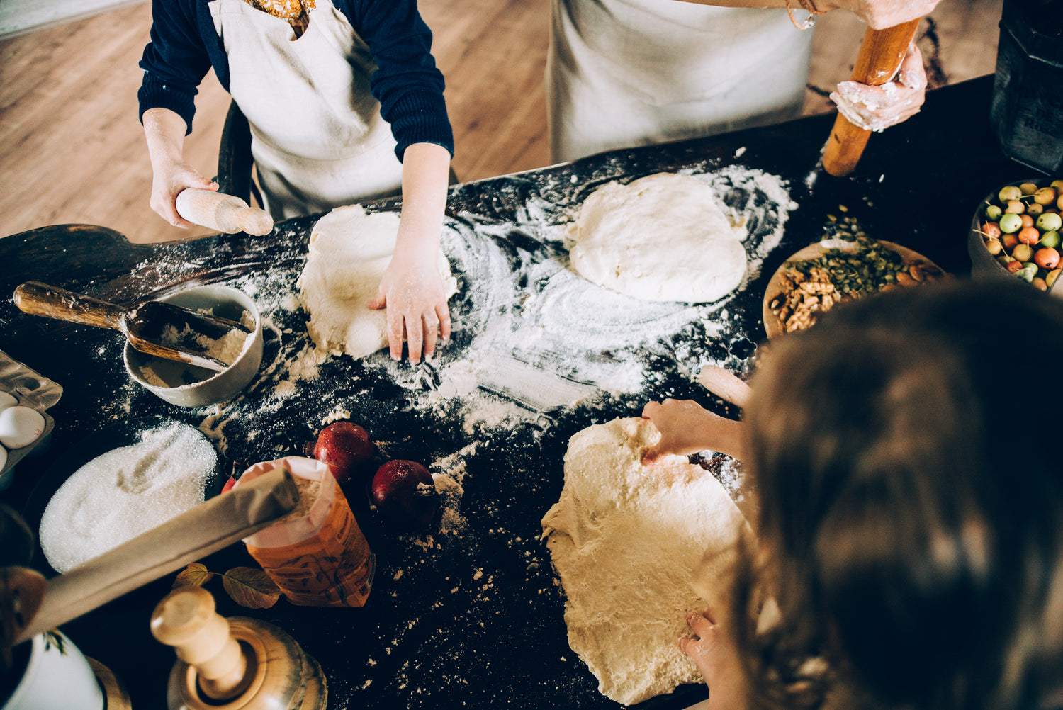 a group of people around a table preparing pierogi dough and preparing fillings for dumplings. 